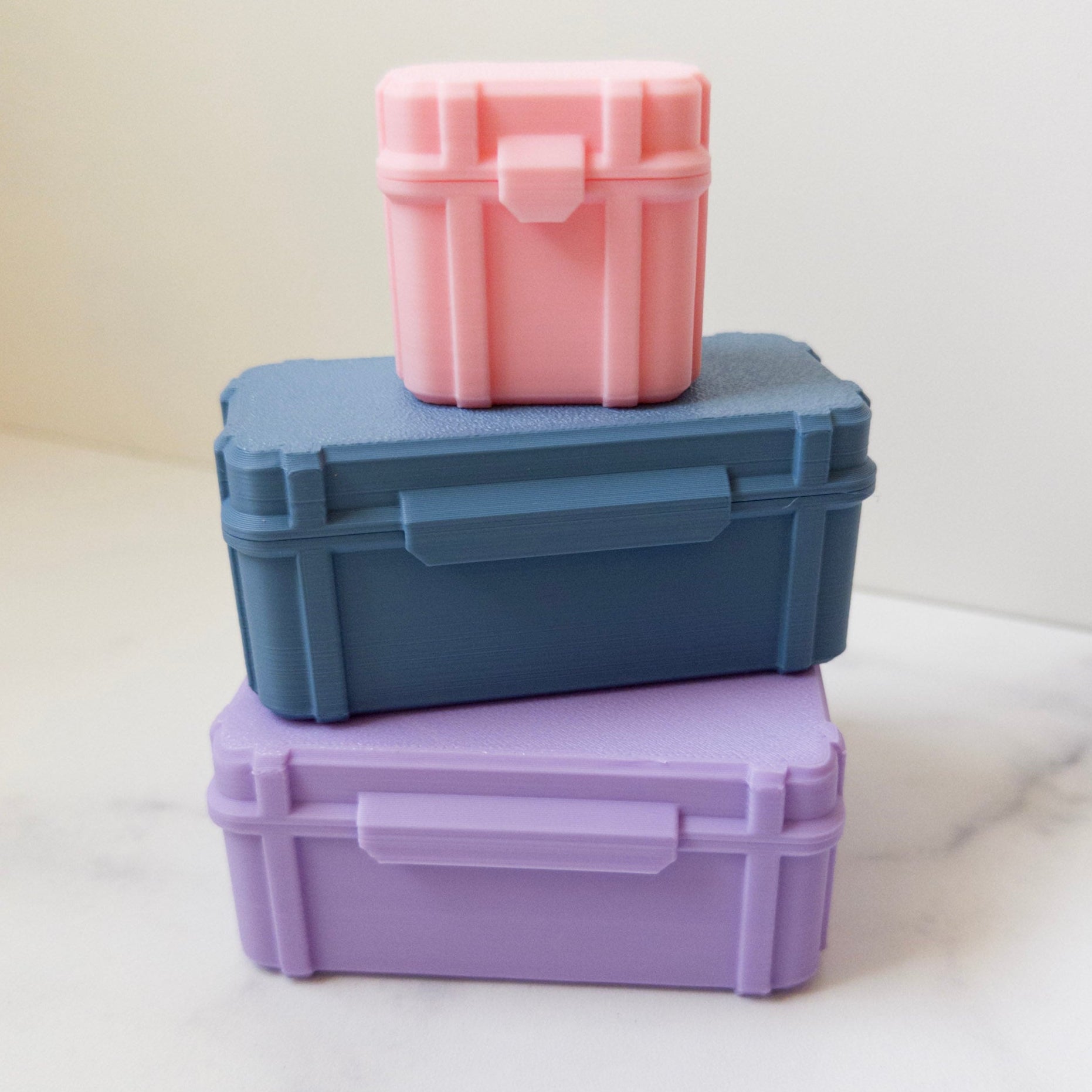 Three colorful peptide storage boxes stacked on a light surface with a white background