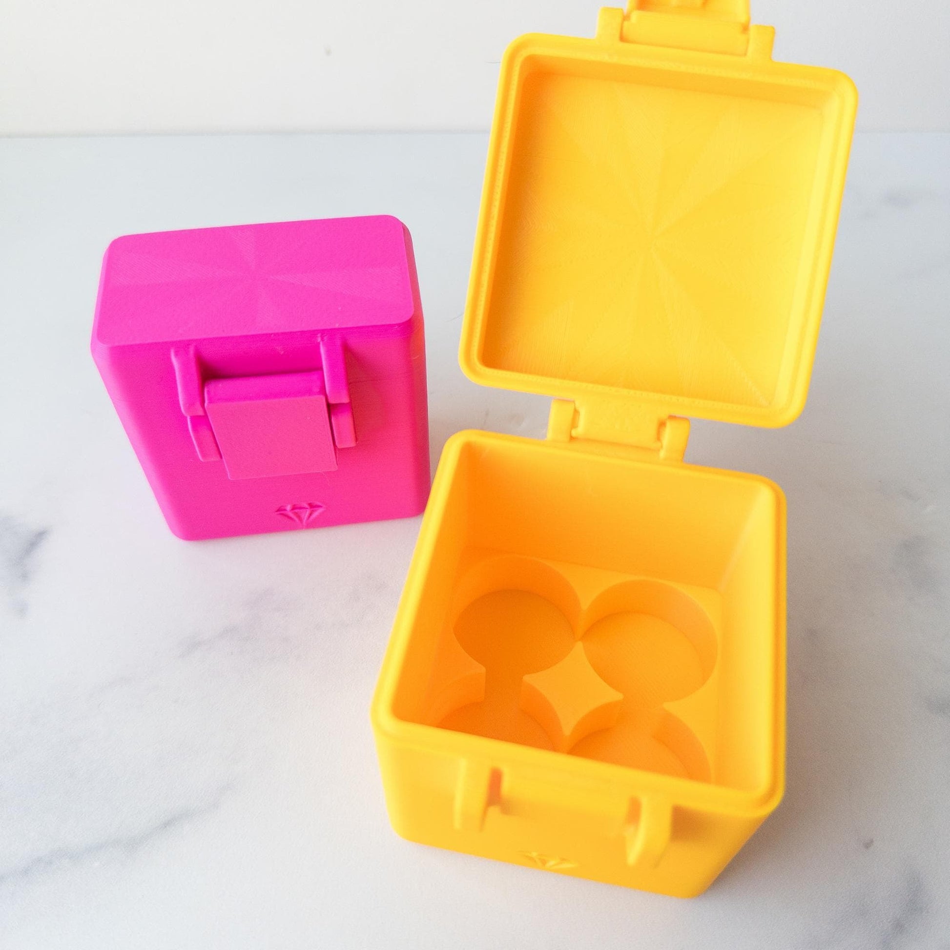 two colorful plastic containers, one pink and one yellow, placed on a white surface.