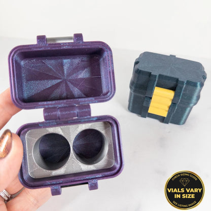 A hand holding a purple container with two black objects inside, and a black box with a yellow handle next to it.