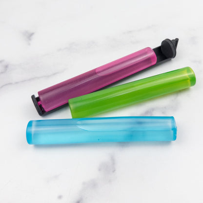 three colorful plastic tubes or containers, including a pink tube, a green tube, and a blue tube, arranged on a marble surface.