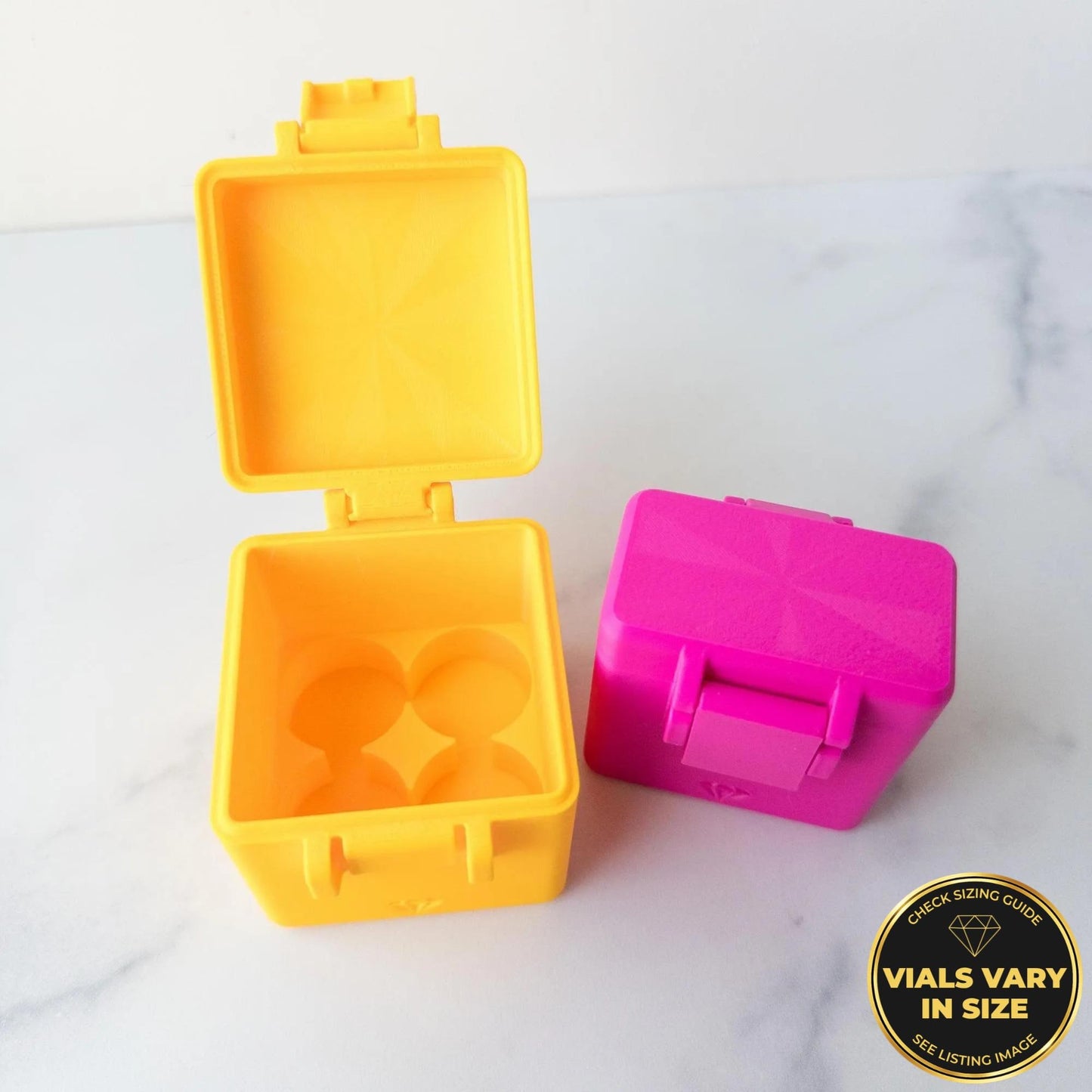 two colorful plastic containers, one yellow and one pink, placed on a marble surface.