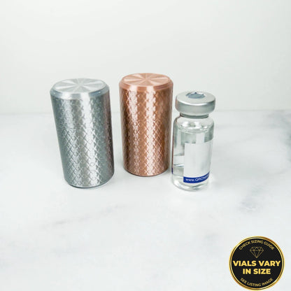 three cylindrical objects, including a silver object, a copper object, and a small glass bottle, placed on a white surface.