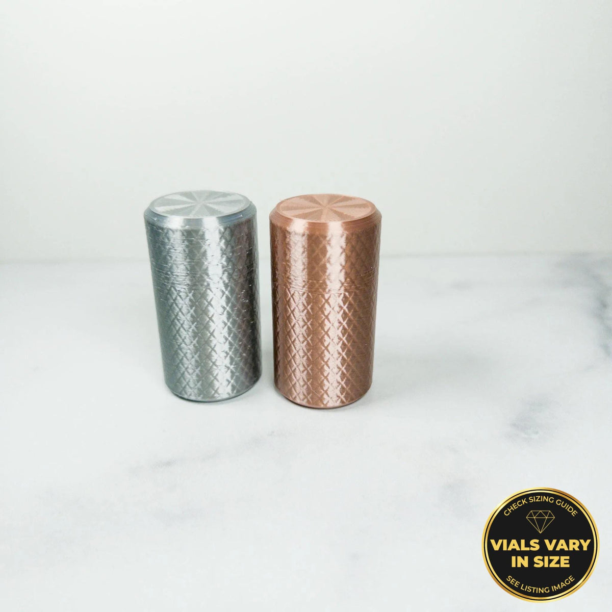 Two cylindrical objects, one silver and one copper, are placed on a white marble surface.