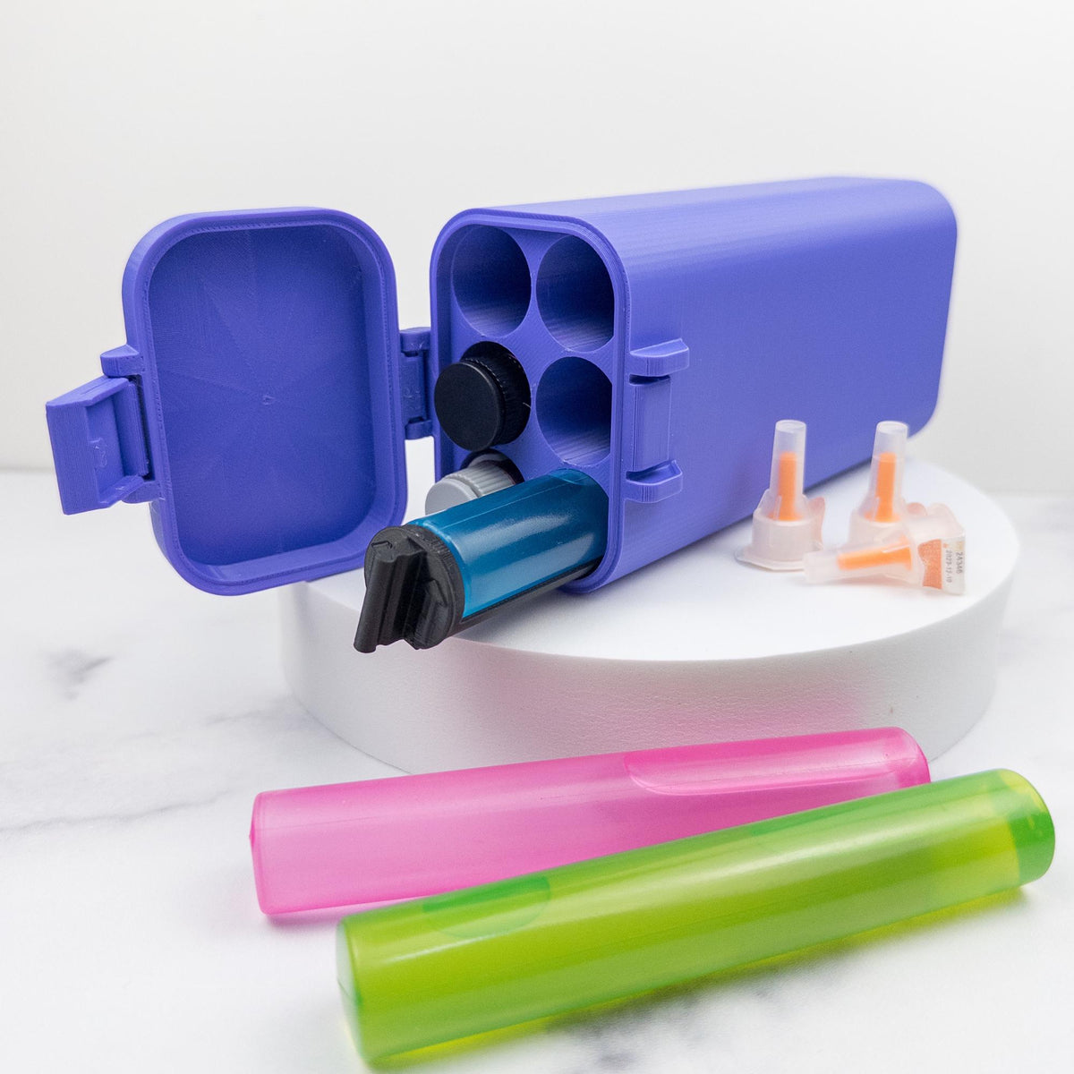 A purple container with a blue and black cap, along with several colorful plastic tubes and pens, are displayed on a white surface.
