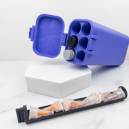 a blue plastic container with six compartments, a white hexagonal box, and a black plastic container with orange and white packets.