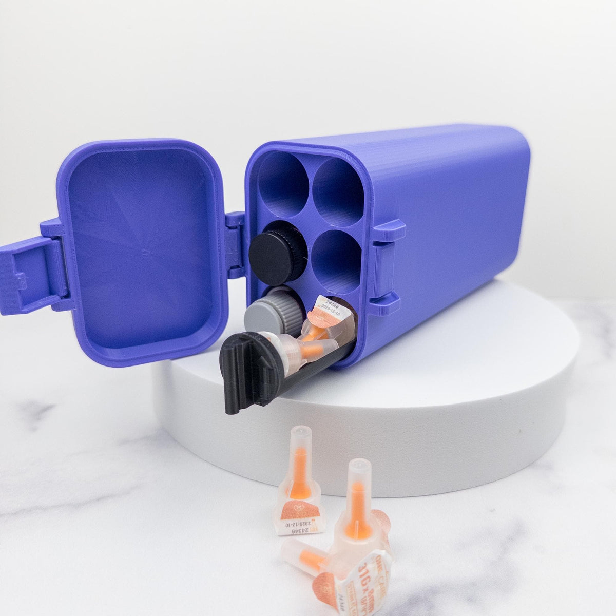 A blue plastic container with a black lid is open, revealing several small orange and white containers inside.