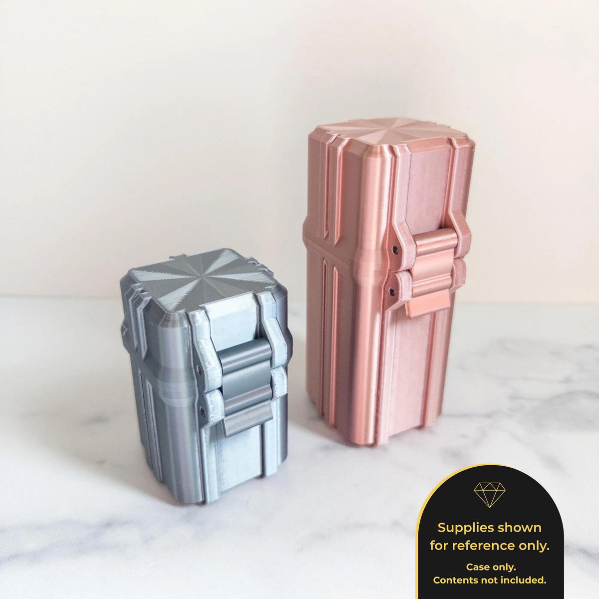 two metallic containers, one silver and one pink, placed on a marble surface.