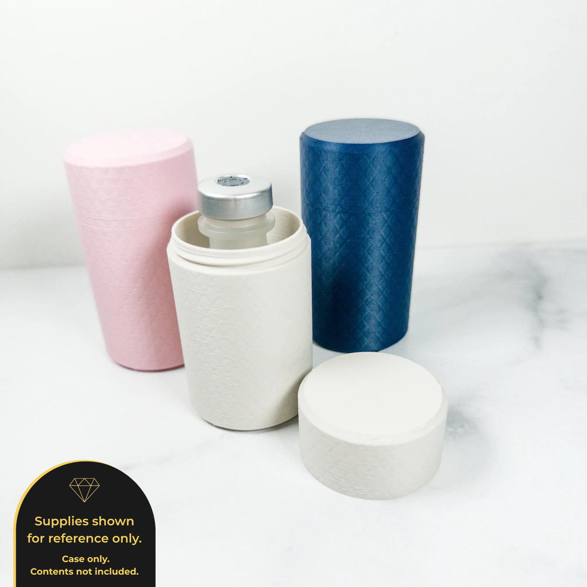 three cylindrical containers with lids, one pink, one white, and one blue, placed on a white surface.